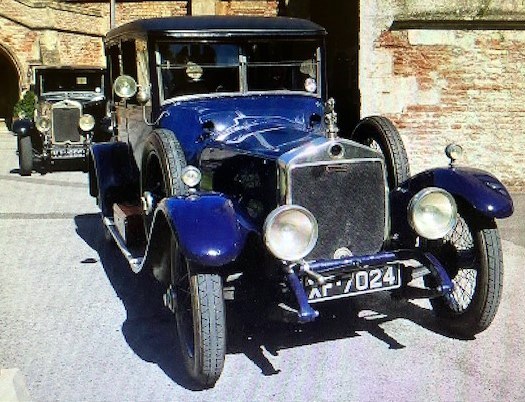 People gathered around Lanchester motor cars